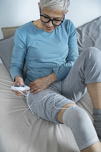 妇女在家里用导十电袜进行膝物理治疗图片