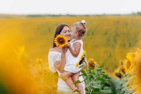 motherday幸福的母亲和女儿在田里有向日葵母亲和女婴在户外玩得开心家庭概念母亲和女婴在田里家庭概念图片