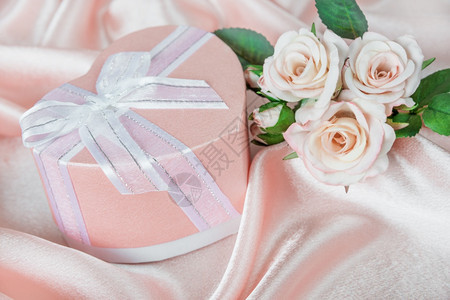 粉红玫瑰和礼品盒在丝织布背景上用弓头贺卡空白图片