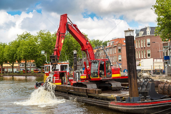 在一个美丽的夏日从阿姆斯特丹的运河中挖出泥浆的土机图片