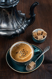 蓝色古董杯中的黑咖啡和旧木板上的古董银罐子图片