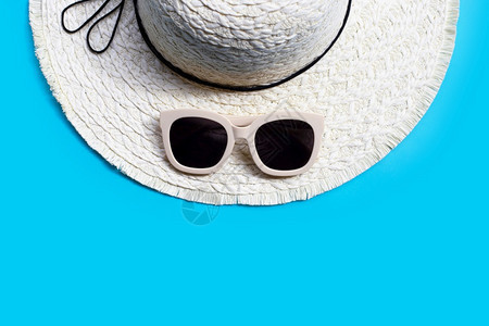 戴着蓝色背景的暑假帽子太阳镜享受假日概念复制空间图片