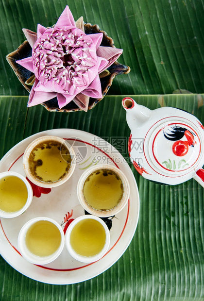 在陶瓷杯和香蕉叶上的锅里放香草花茶图片