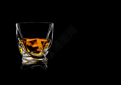 以黑色背景和反射为底色的晶体现代豪华玻璃杯中的威士忌文本空间图片