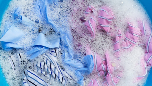 彩色衣服的顶部视图浸泡在粉末洗涤水溶解中图片
