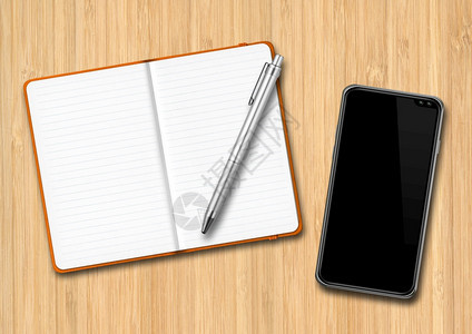木制桌上的开放笔记本和智能手机笔记本和智能手机放在木制桌上图片