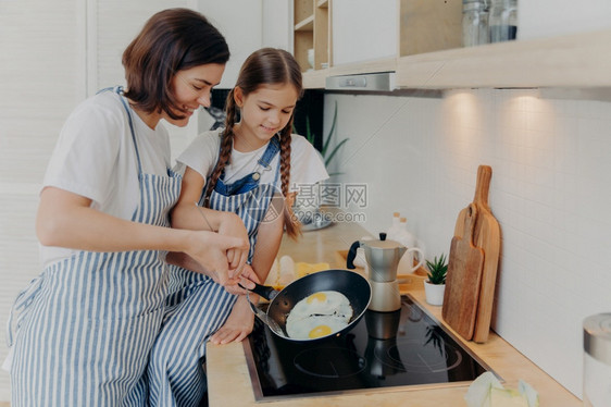 母亲在厨房教女儿煎鸡蛋图片