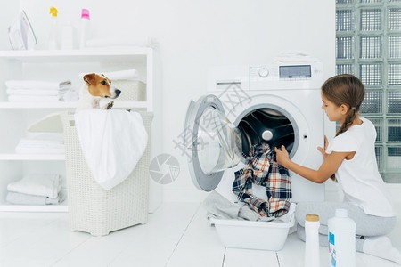 小女孩有乐趣和洗衣机里面摆姿势图片