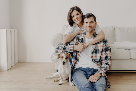 丈夫妻子和狗在新住宅的客厅里一起摆姿势享受舒适图片