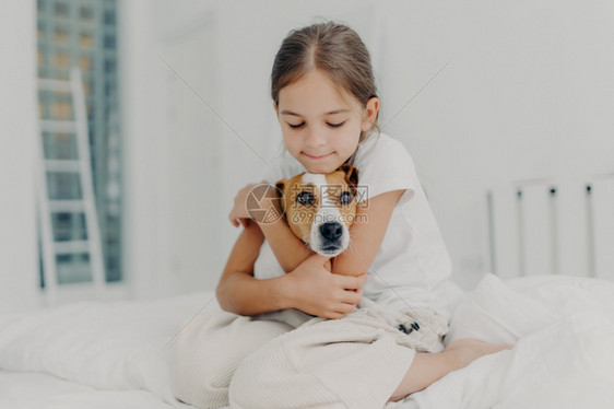 小女孩拥抱狗呆在床上图片