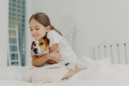 穿着散装睡衣坐在床上对宠物表示爱图片