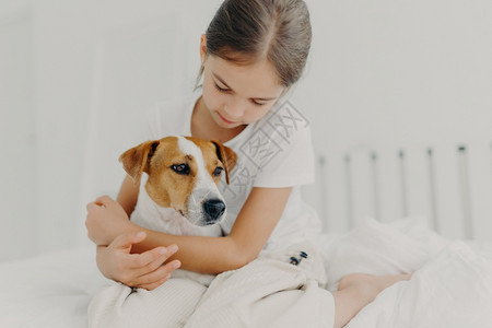 穿着散装睡衣坐在床上对宠物表示爱图片