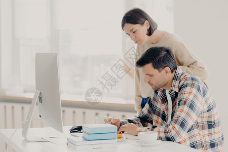 夫妻共同撰写书面报告检查信息坐在电脑前面喝咖啡穿便服合作团队图片
