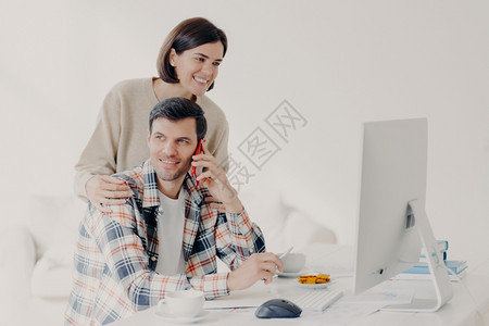 丈夫在接电话妻子微笑的看着丈夫的电脑图片