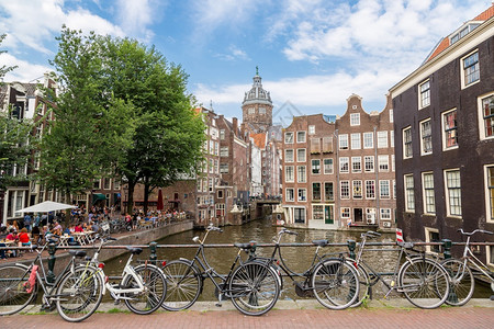在一条桥上骑自行车穿越阿姆斯特丹运河在夏日图片
