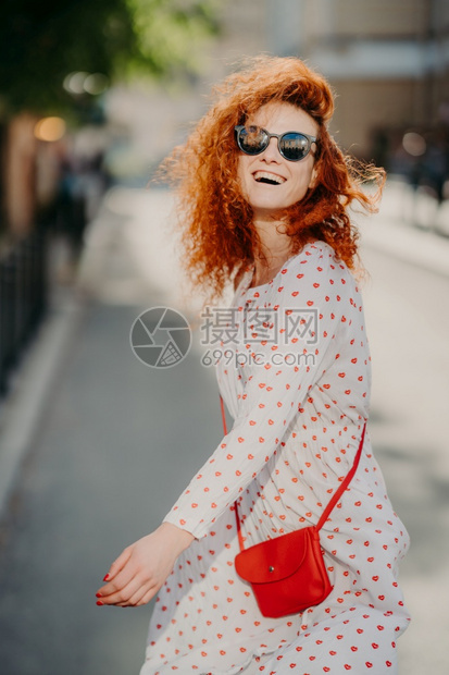 无忧虑的红发女人笑得很开心在城市户外自由度日穿太阳眼镜长袖衣服带红包玩得开心享受娱乐时间人与生活方式图片