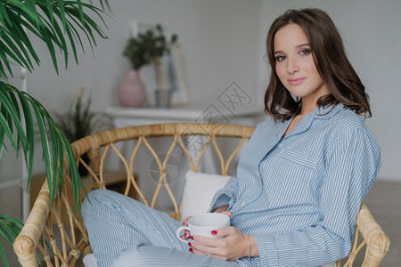 穿着睡衣喝热咖啡和拿铁室内舒适的化妆品有周末人和放松的概念图片