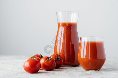 纯西红柿和一杯新鲜饮料隔绝于白底番茄汁由透明杯子的蔬菜制成健康饮品背景图片