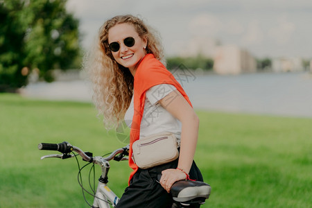 漂亮年轻女子骑着运动自行车在草坪上停下图片