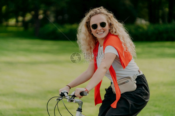 美丽的年轻女子在户外骑着自行车图片
