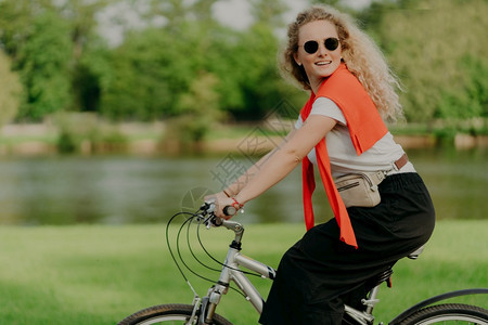 快乐女子骑着自行车在公园河道边图片