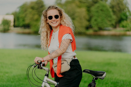 喜悦的年轻女子骑着自行车在公园河道边图片