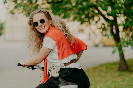 快乐女子骑着自行车在公园河道边图片