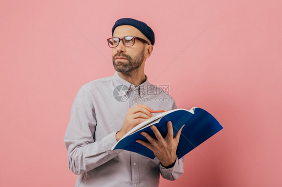 中年男人手上拿着一本蓝色的笔记本在做笔记图片