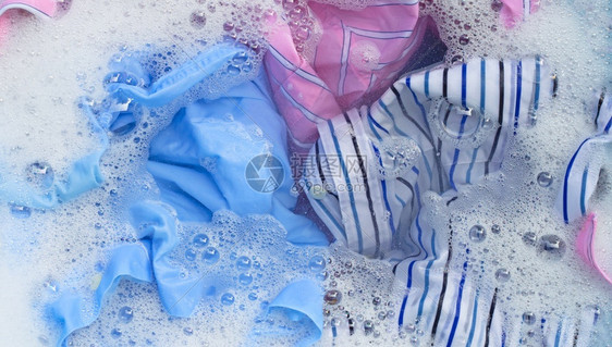 彩色衣服的顶部视图浸泡在粉末洗涤水溶解中图片