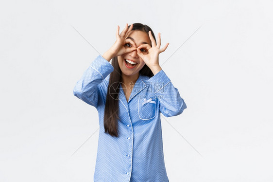 穿着蓝色睡衣快乐的亚洲女孩穿着假眼镜笑在过夜派对上与兄弟姐妹玩乐图片