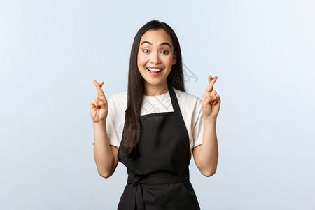 咖啡店小生意和开办概念乐观可爱的亚洲女服务员交叉手指祝好运在黑色围裙上做愿望祈祷或恳求的畅快酒吧乐观可爱的亚洲女服务员交叉手指祝图片