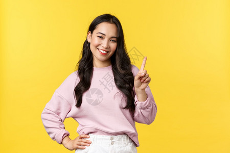 人们的情感生活方式和时装概念微笑着快乐的英俊亚洲女孩提供建议用一只手指来解释规则点站立黄色背景人们的情感点站立黄色背景图片