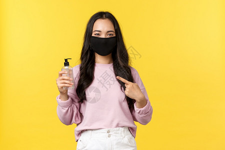 19岁社会维生的活方式防止传播的概念脸面遮罩指着手防疫剂在科罗纳流行期间照顾个人卫生黄色背景19岁防止传播的概念面罩指着防疫剂黄图片