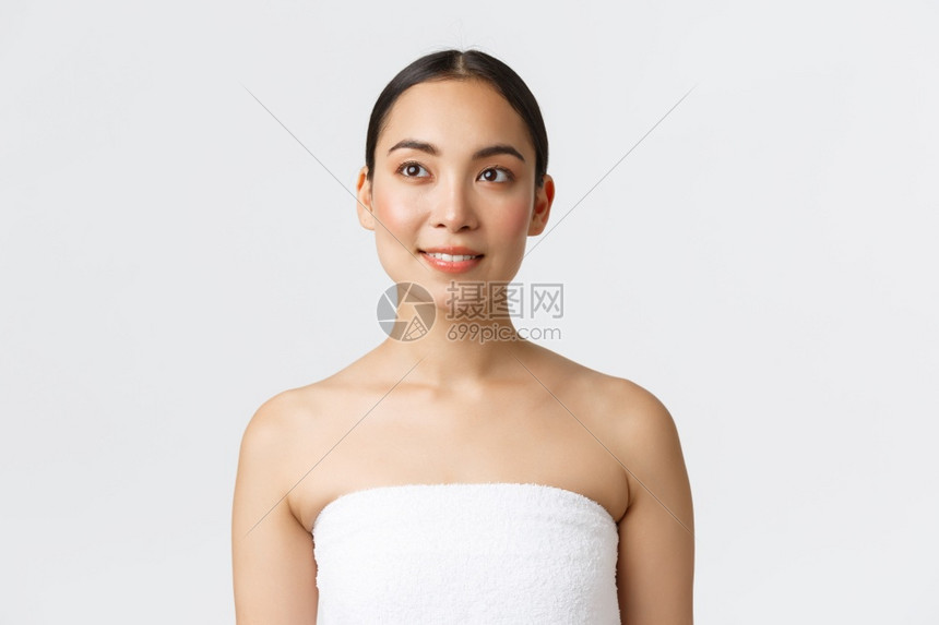 美貌容学和温泉沙龙概念白毛巾中的年轻美丽亚洲女穿着白毛巾带快乐的笑容带着在左边照顾身体站着卫生间施用皮肤护理产品美容学和温泉沙龙图片