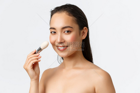 美貌的亚洲妇女赤裸地露着脸用化妆刷品对照相机微笑白背景皮肤护理妇女美容卫生和个人护理概念裸着用化妆刷照相机微笑图片