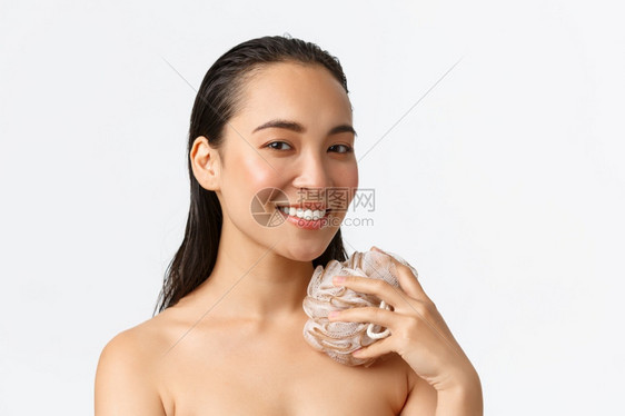 美貌的亚洲女孩洗澡用海绵淋浴用照相机白背景照相机洗脸和微笑皮肤保健妇女美貌卫生和个人护理概念美貌的亚洲女孩淋浴用海绵洗脸和微笑白图片