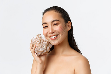美貌的亚洲女孩洗澡用海绵淋浴用照相机白色背景洗脸和微笑复制空间皮肤护理妇女美容卫生和个人护理概念美貌女亚洲女孩淋浴洗脸和在照相机图片