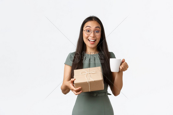 终于收到线上商店的订单站着白色背景兴奋快乐的亚洲女喝着咖啡接受家庭分娩带着愉快的微笑站着白色背景图片