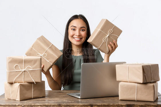 小型商业所有者创办商和电子务概念微笑着的亚洲妇女得到很多订单坐在桌上用笔记本电脑和包装客户购买货物装箱船白色背景小型商业所有者开图片