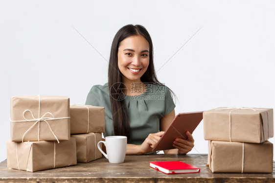 小型商业主创办和电子务概念笑的女商人在家工作包装售出的物品包装船订单的箱通过数字平板管理网上商店小企业主开办商和电子务概念笑的女图片