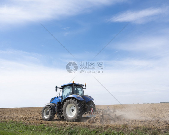 夏季在蓝天空下弗朗特以北的兰蓝天为的田地上用拖拉机的农民图片