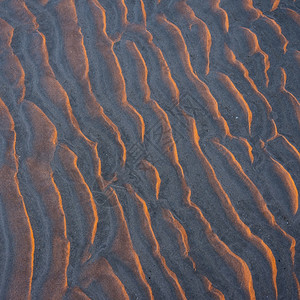 在日落的温暖光照下沙滩上波的抽象模式图片
