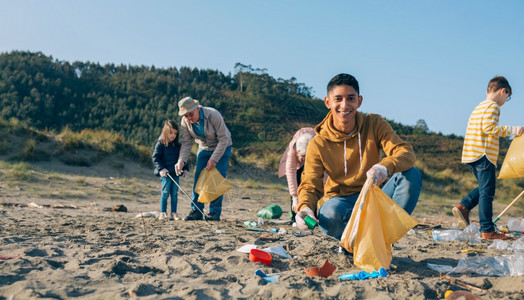 年轻人在海滩上和一群志愿者起捡垃圾背景图片
