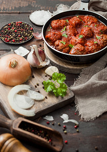 番茄酱里的传统牛肉丸煎锅里有胡椒大蒜和柑橘还有洋葱和木制的盐图片