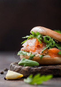 新鲜三明治文鱼和百吉饼野生火箭和奶油酪柠檬和胡椒在木头上图片