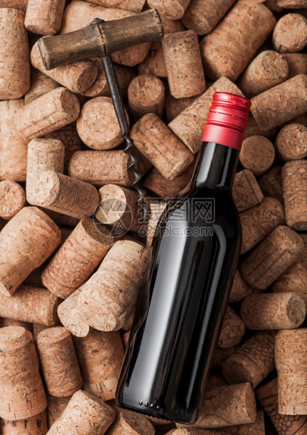 一瓶红葡萄酒和古老的软木塞在各种葡萄酒软木背景之上图片