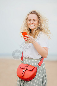 穿着时装携带包袋持有现代手机向朋友提供短信反馈在社交网络上读她照片下的评论图片