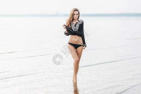 比基尼穿的可爱女展示出完美的身体形状站在海岸线上有细的腿迷人外表和化妆魅力在户外泳衣日光浴中放松的迷人女图片