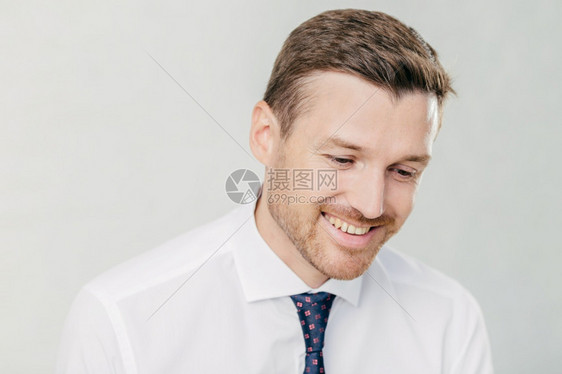 穿着优雅的白衬衫男公司工人快乐地看着他记得一些令人愉快的回忆笑着牙穿带领的优雅白衬衫隔着墙图片