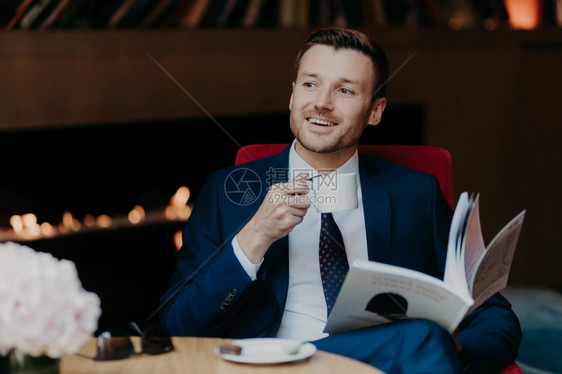 男公司老板在舒适的餐厅里休息用卡布奇诺咖啡杯举行白色子脸上笑容愉快阅读商业日记将漂亮女人放在一边下班后有闲暇时间图片